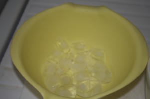 To cool egg yolks after adding hot syrup, prepare a bowl with a layers of ice cubes...