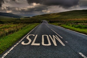 Photo of road with "slow" sign on asphalt.