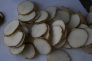 No need to peel potatoes. Slice thinly and quickly. To avoid them turning brown, spread potatoes on a greased cookie sheet.